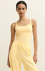 Load image into Gallery viewer, Woman wearing a yellow tank top and pants against a beige background
