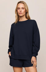 Load image into Gallery viewer, Woman wearing a navy blue oversized sweatshirt and shorts on a beige background
