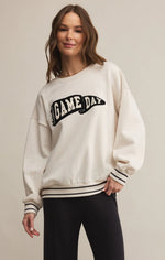 Load image into Gallery viewer, Woman wearing a white sweatshirt with &#39;GAME DAY&#39; text on a beige background
