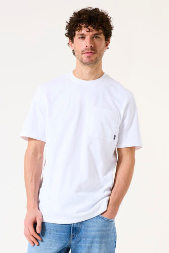 Man wearing a white t-shirt with a small logo on a plain background