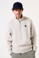 Load image into Gallery viewer, Man wearing a beige half-zip sweatshirt with a small logo on a white background
