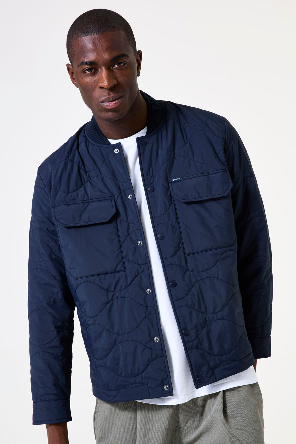 Navy blue quilted man's jacket with snap closure and front breast flap pockets. 
