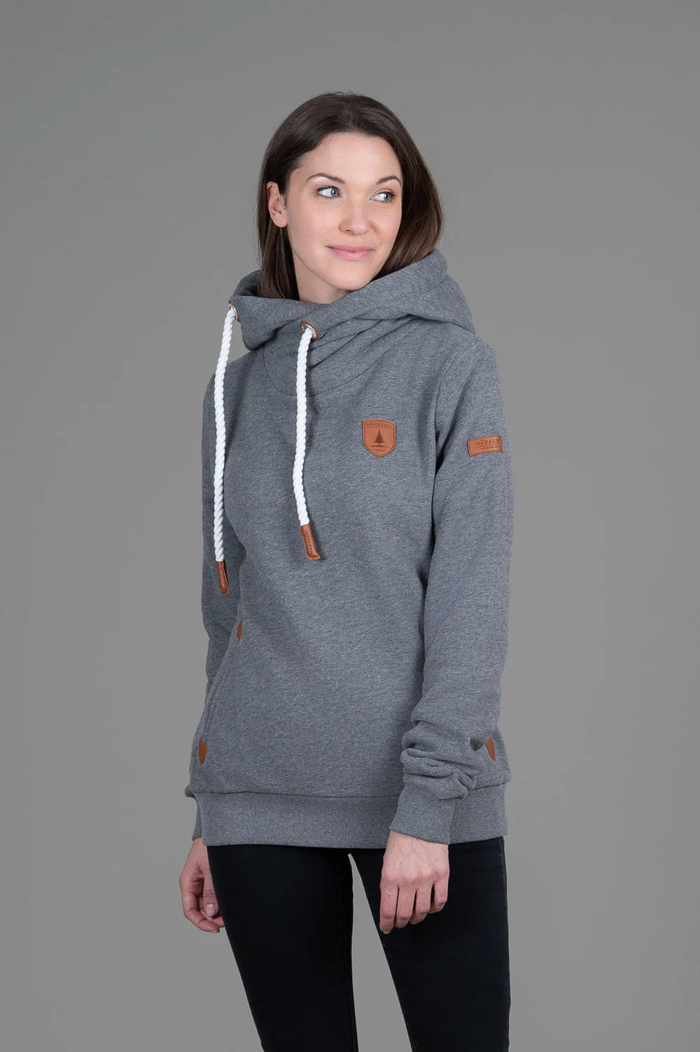 Woman wearing a gray hoodie with brown accents on a gray background