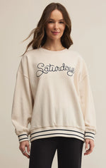Load image into Gallery viewer, Woman wearing a cream sweatshirt with &#39;Saturday&#39; text on a beige background
