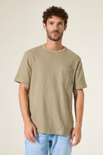 Load image into Gallery viewer, Man wearing a green t-shirt with a chest pocket on a beige background
