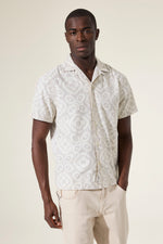 Load image into Gallery viewer, Man wearing a white and brown patterned shirt and beige pants on a plain background
