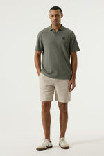 Load image into Gallery viewer, Man wearing a green polo shirt and beige chino shorts on a white background
