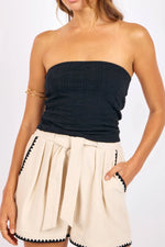 Load image into Gallery viewer, Woman wearing a strapless black tube top and beige shorts with black trim on a white background

