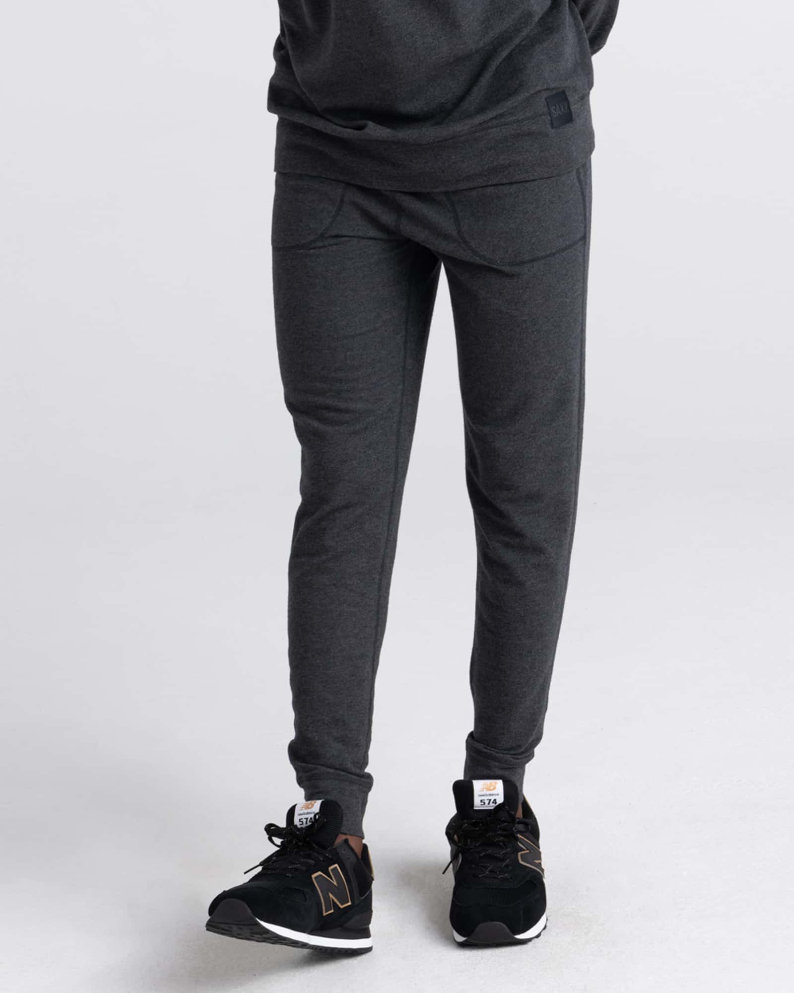 Person wearing black heather jogger pants and black sneakers on a white background