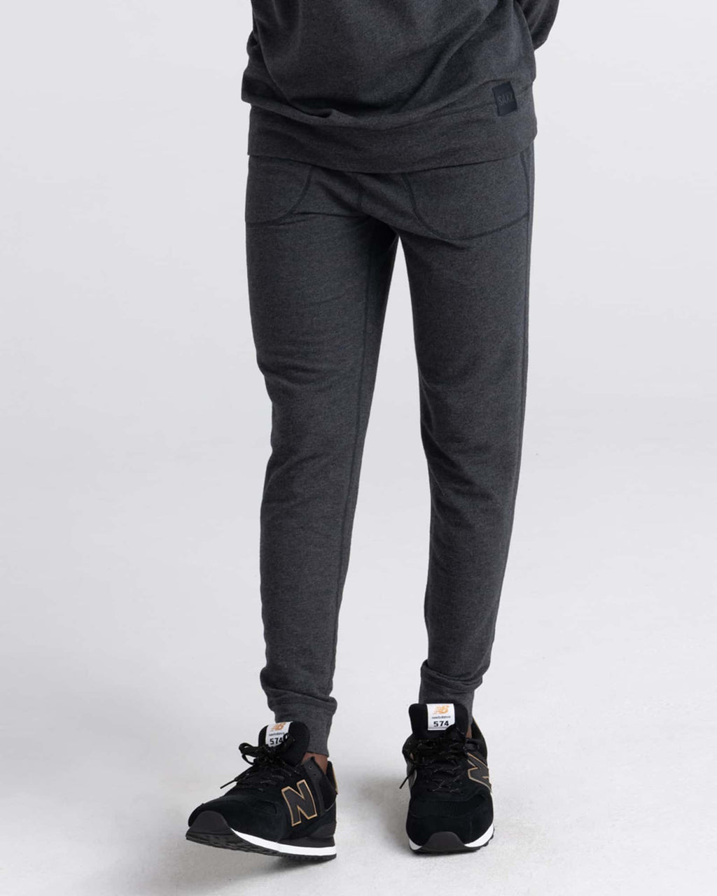 Person wearing black heather jogger pants and black sneakers on a white background