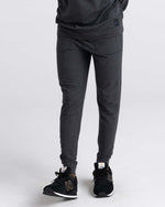 Load image into Gallery viewer, Person wearing black heather jogger pants and black sneakers on a white background
