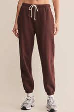 Load image into Gallery viewer, Brown sweatpants with a white drawstring on a beige background

